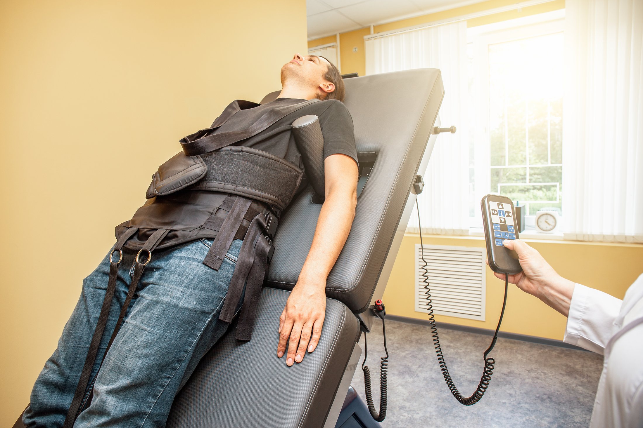 Decompression treatment underway — the patient in the harness on the inclined table, the clinician at the controls