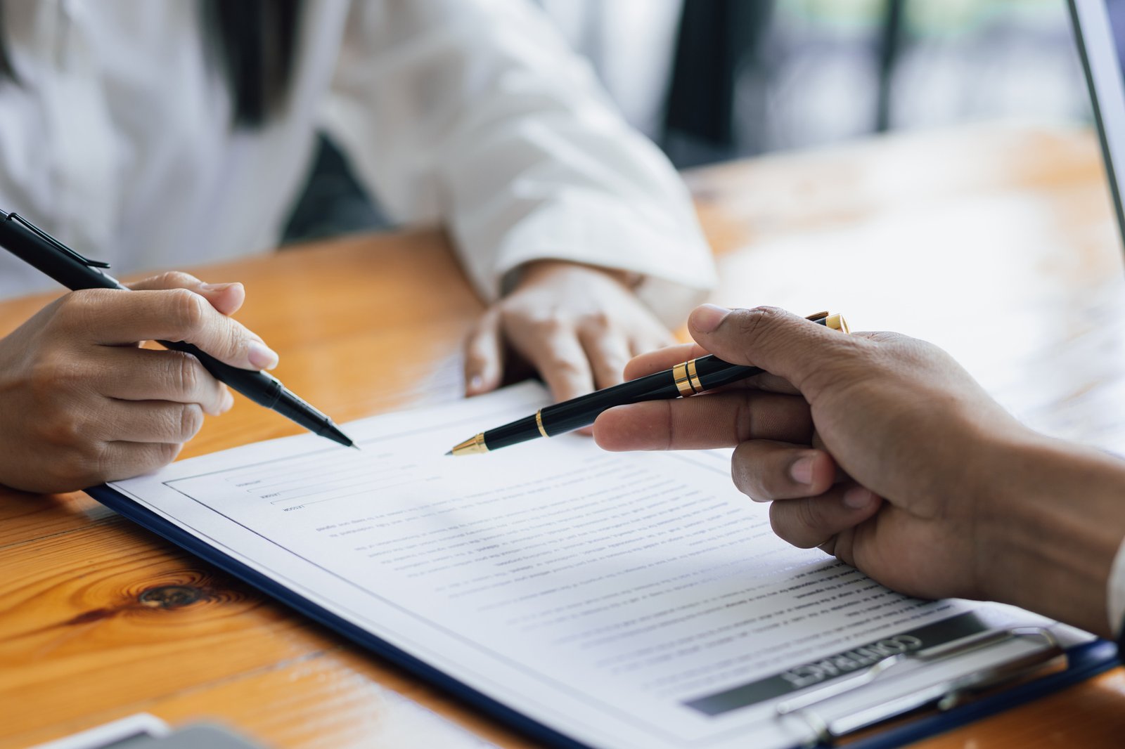 Two people reviewing a printed agreement together, pens in hand